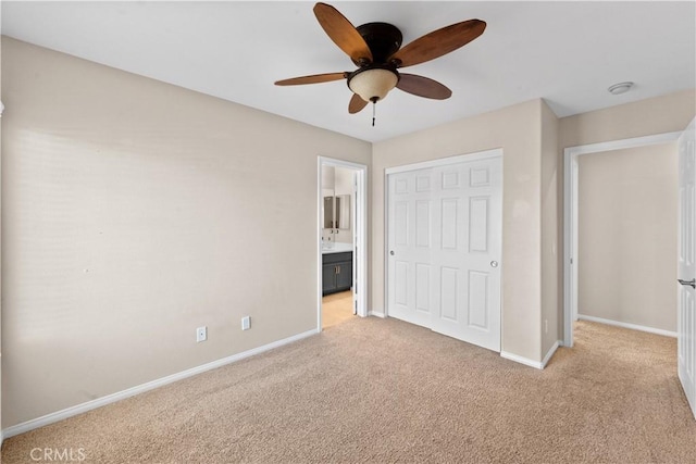 unfurnished bedroom with a closet, light colored carpet, a ceiling fan, ensuite bath, and baseboards