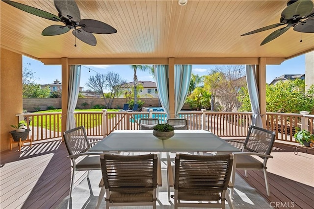 wooden deck with outdoor dining space, a fenced backyard, and ceiling fan