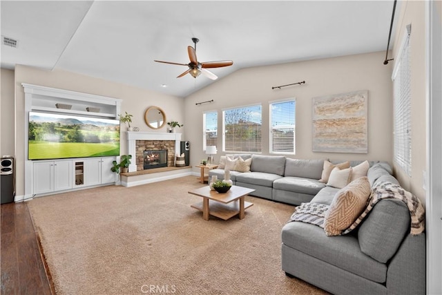 living room featuring a fireplace, lofted ceiling, visible vents, ceiling fan, and baseboards