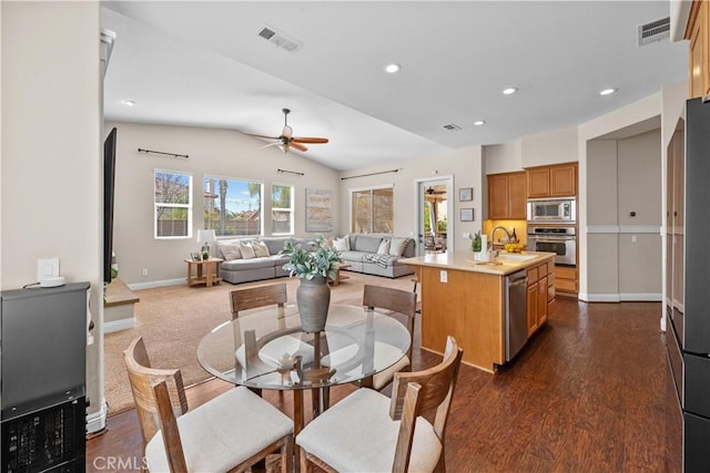 kitchen with stainless steel appliances, visible vents, open floor plan, a kitchen island with sink, and a sink