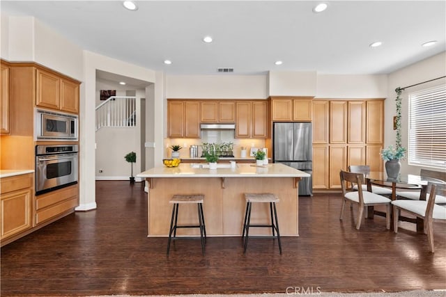 kitchen with appliances with stainless steel finishes, light countertops, a kitchen island, and visible vents