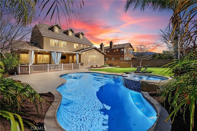 view of swimming pool with a patio area, a pool with connected hot tub, fence, and a yard