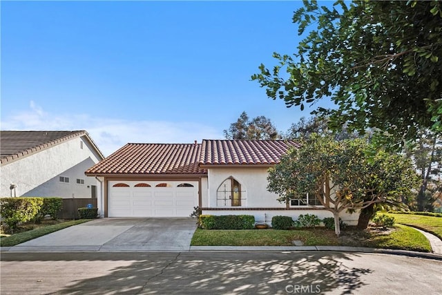 mediterranean / spanish home with concrete driveway, a tiled roof, an attached garage, and stucco siding