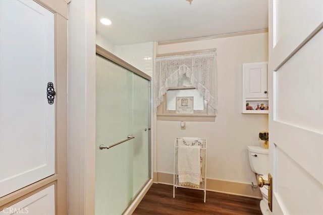 bathroom with toilet, a shower stall, baseboards, and wood finished floors