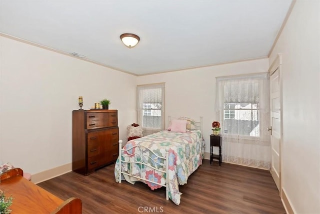 bedroom with ornamental molding, dark wood-type flooring, visible vents, and baseboards