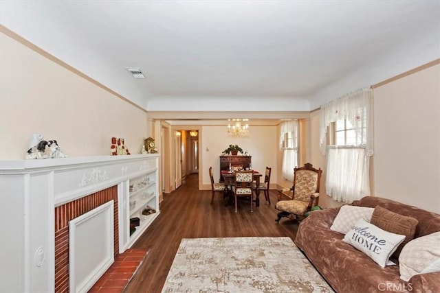 living area featuring a fireplace, visible vents, a chandelier, and dark wood-style flooring