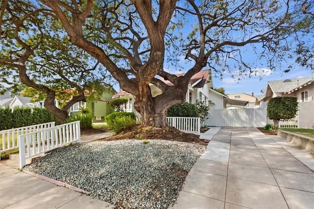 view of property hidden behind natural elements featuring a fenced front yard and a residential view