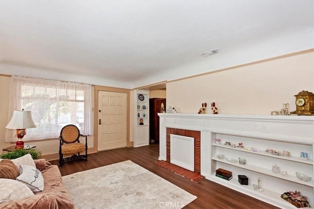 living area with a fireplace, visible vents, and dark wood-type flooring