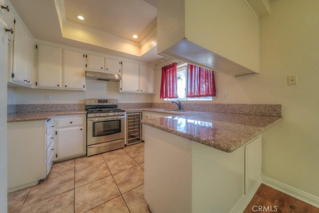 8371 Hawthorne St, Rancho Cucamonga, CA 91701 - kitchen with stainless steel range with gas cooktop, under cabinet range hood, a peninsula, a raised ceiling, and white cabinetry