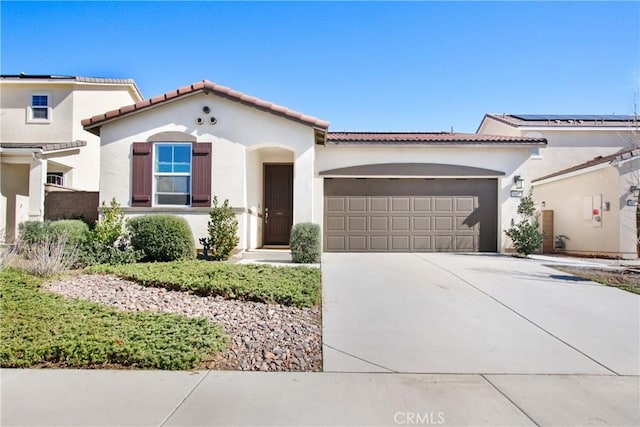 mediterranean / spanish-style home with a garage, driveway, a tiled roof, and stucco siding