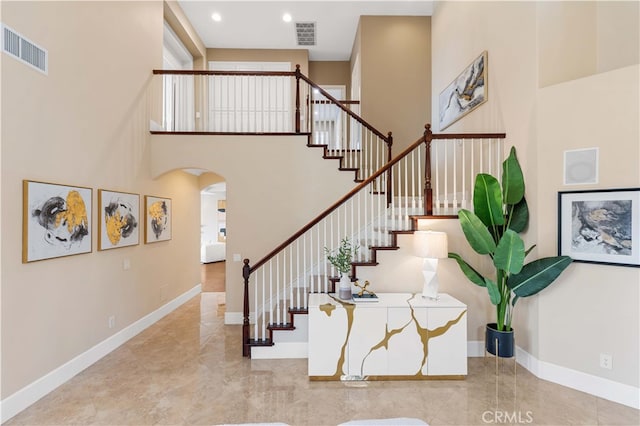 stairs featuring visible vents, a towering ceiling, and baseboards