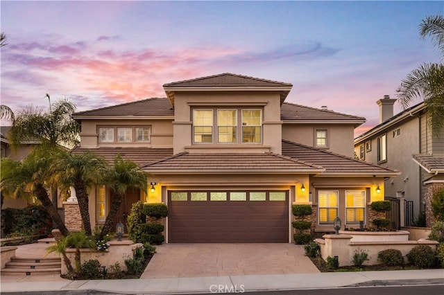 prairie-style home with a garage, a tile roof, concrete driveway, and stucco siding