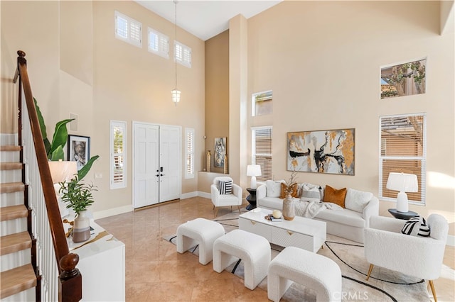 tiled living area with a high ceiling, stairway, plenty of natural light, and baseboards