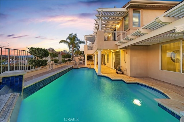 pool at dusk with fence, an outdoor pool, and a pergola