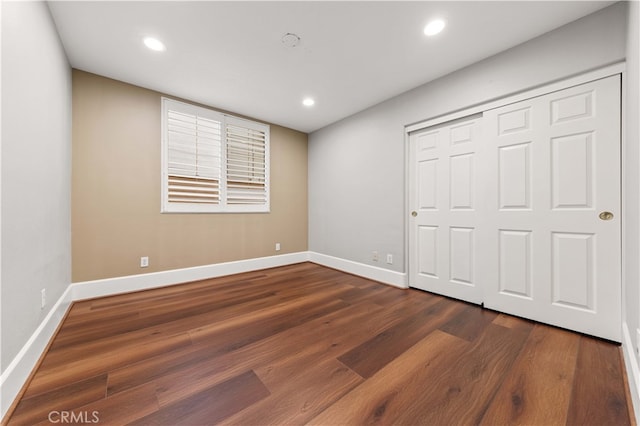 unfurnished bedroom featuring dark wood-type flooring, recessed lighting, a closet, and baseboards