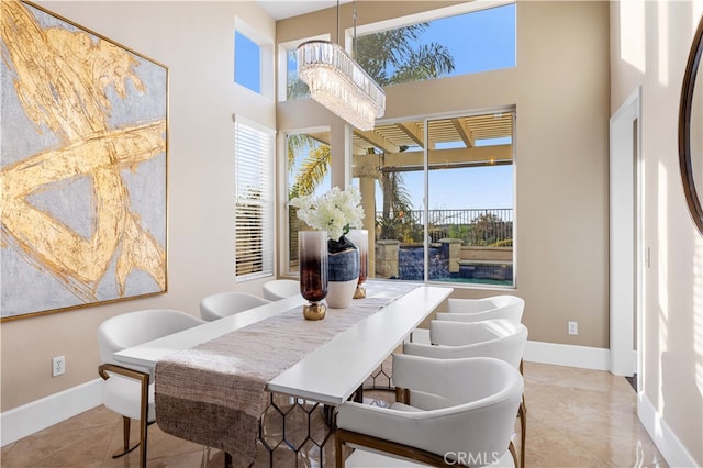 dining area with a towering ceiling, baseboards, and a notable chandelier