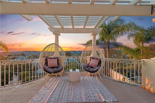 balcony at dusk with a mountain view and a pergola