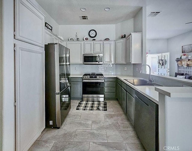 68262 Pasada Rd, Cathedral City, CA 92234 - kitchen with appliances with stainless steel finishes, backsplash, light countertops, a peninsula, and white cabinetry