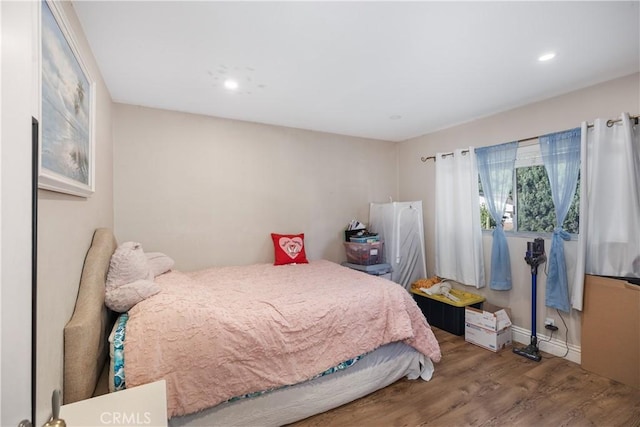 bedroom with baseboards, wood finished floors, and recessed lighting