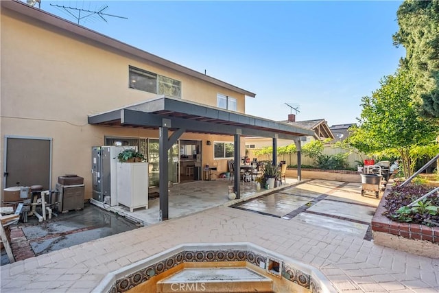 rear view of house with a patio area, fence, and stucco siding