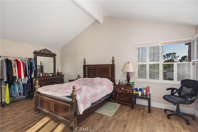 bedroom with lofted ceiling with beams, wood finished floors, and baseboards