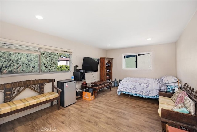 bedroom featuring wood finished floors, freestanding refrigerator, and recessed lighting