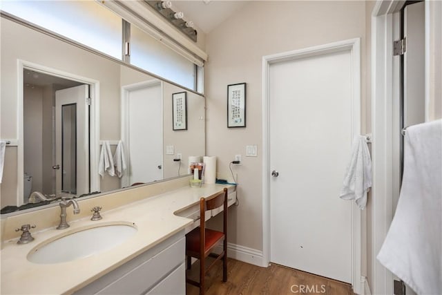 bathroom with vaulted ceiling, wood finished floors, and vanity