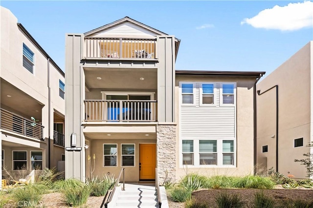 view of front of house featuring a balcony and stucco siding