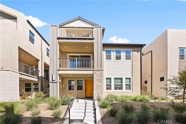 townhome / multi-family property with a balcony and stucco siding