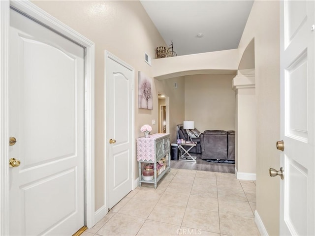 hall featuring baseboards, visible vents, arched walkways, and light tile patterned flooring