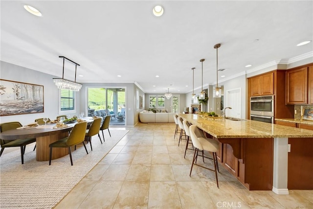 kitchen featuring double oven, pendant lighting, a sink, and light stone countertops