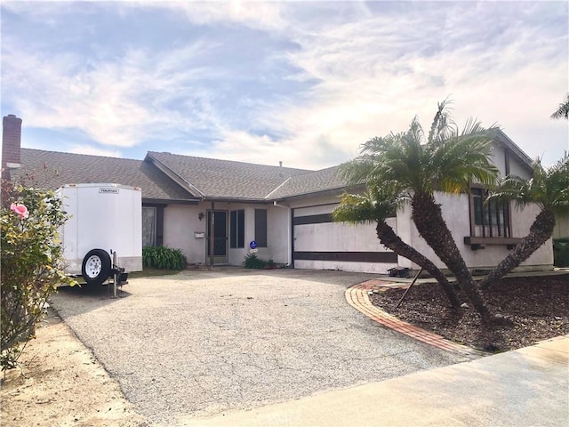 single story home with stucco siding, an attached garage, roof with shingles, and driveway