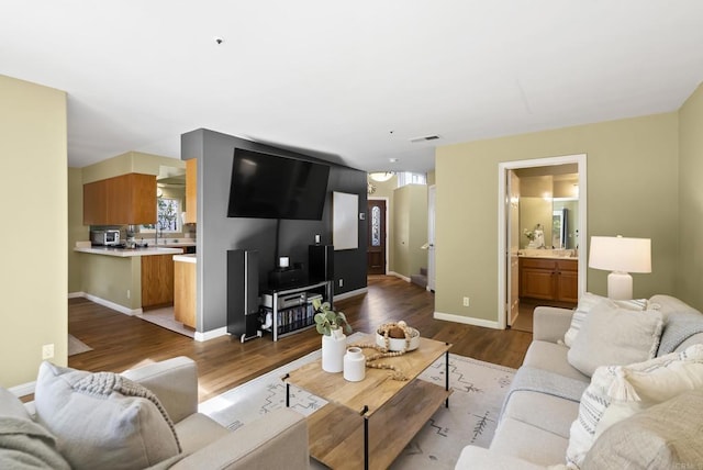 living area with light wood-style floors, visible vents, and baseboards