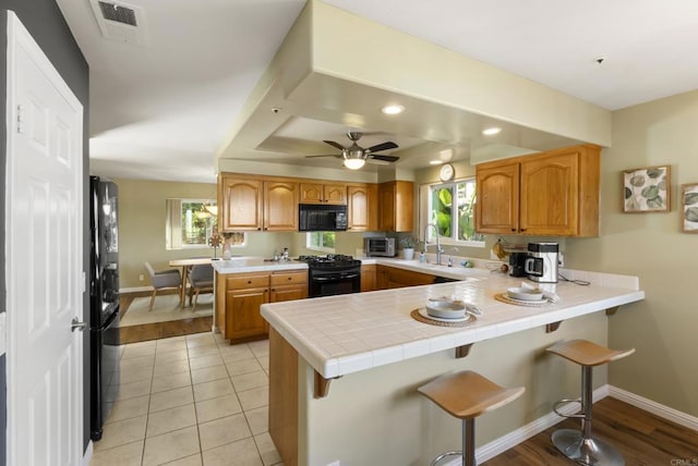 kitchen with black appliances, a peninsula, and a wealth of natural light