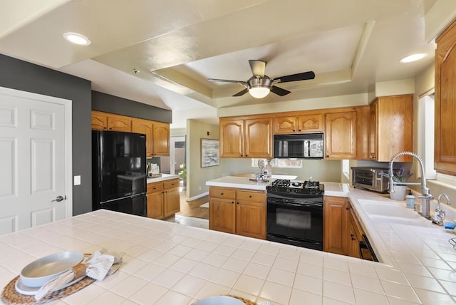 kitchen with tile counters, a raised ceiling, a sink, ceiling fan, and black appliances