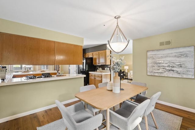 dining space featuring wood finished floors, visible vents, and baseboards