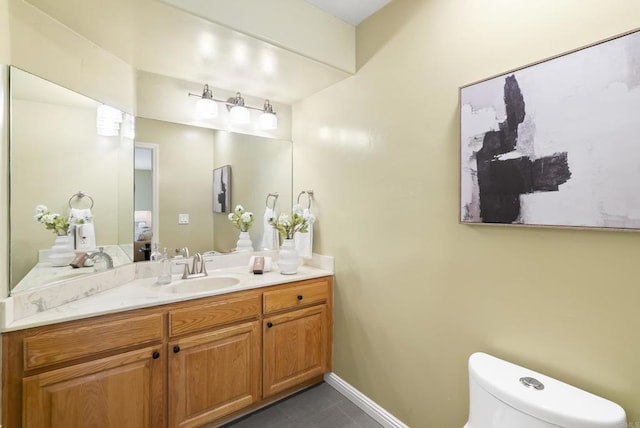 half bath featuring baseboards, vanity, toilet, and tile patterned floors