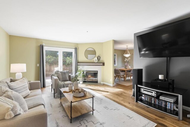 living room featuring a glass covered fireplace, baseboards, and light wood finished floors