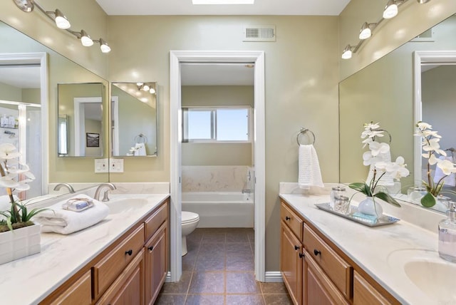 bathroom featuring toilet, a skylight, vanity, visible vents, and a bath