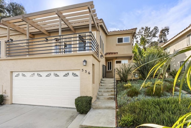 view of front of home featuring stucco siding, a balcony, a garage, driveway, and a tiled roof