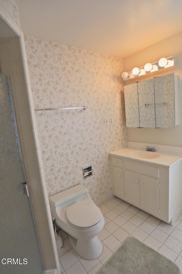 bathroom featuring a shower with door, vanity, toilet, and tile patterned floors