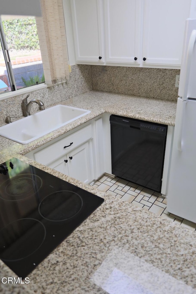 kitchen with dishwasher, a sink, freestanding refrigerator, and white cabinets