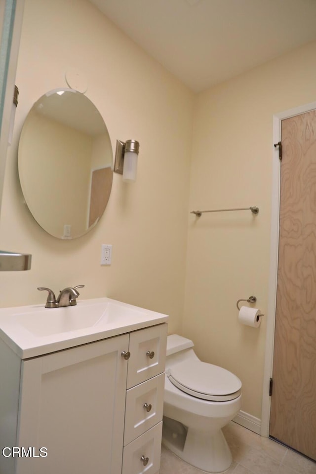 bathroom with toilet, tile patterned floors, baseboards, and vanity