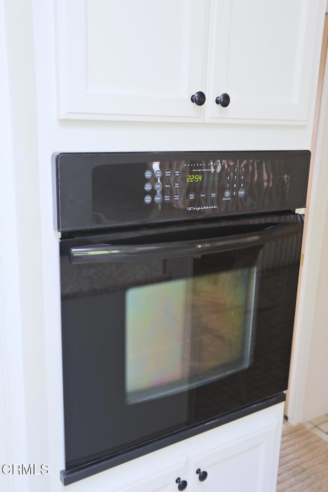 room details with dark countertops, white cabinetry, and black oven