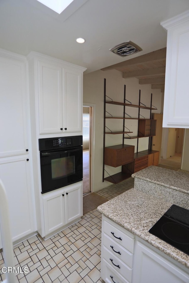 kitchen with cooktop, white cabinetry, visible vents, and oven