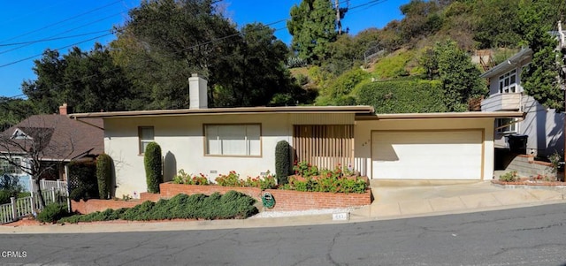 ranch-style house with a garage, concrete driveway, fence, and stucco siding