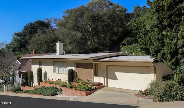 single story home featuring a chimney, stucco siding, concrete driveway, fence, and a garage