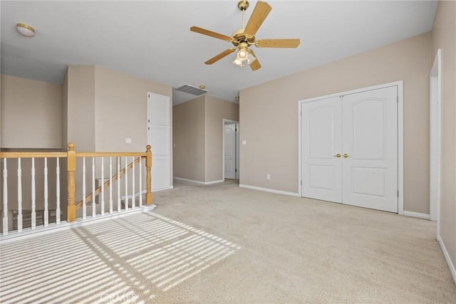 unfurnished room with light carpet, visible vents, baseboards, and a ceiling fan