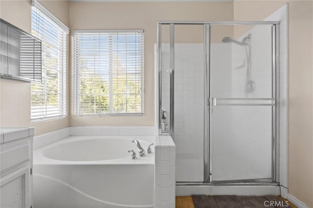 bathroom featuring a stall shower, a garden tub, and vanity