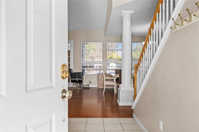 entrance foyer featuring baseboards, light tile patterned flooring, ornate columns, and stairs